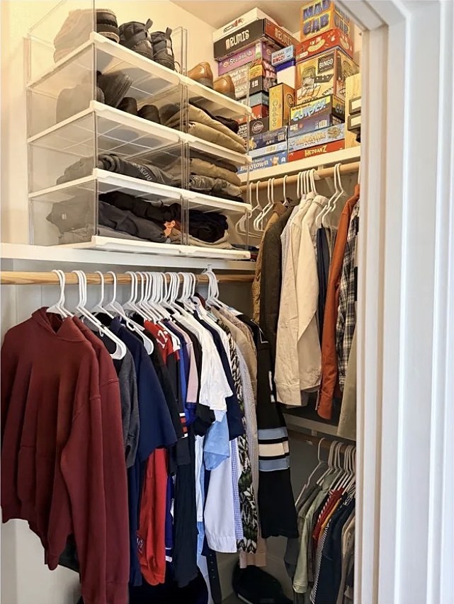 Closet with neatly hung clothes and organized shelves after organizing
