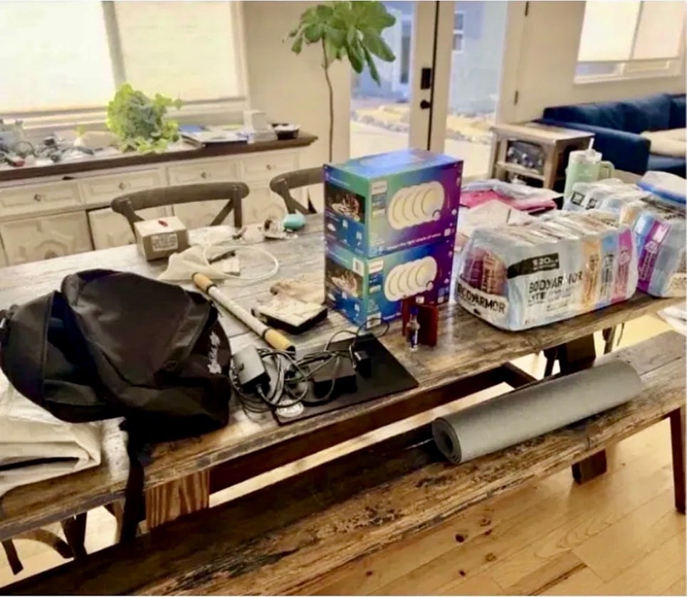 Dining table covered with bags, boxes and cords before organizing